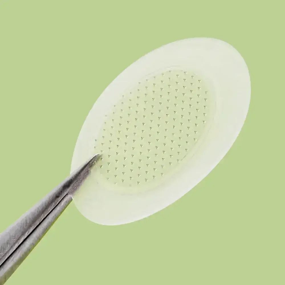 Close-up van een patch met micro-pins. Pincet houdt de patch vast. Groene achtergrond.