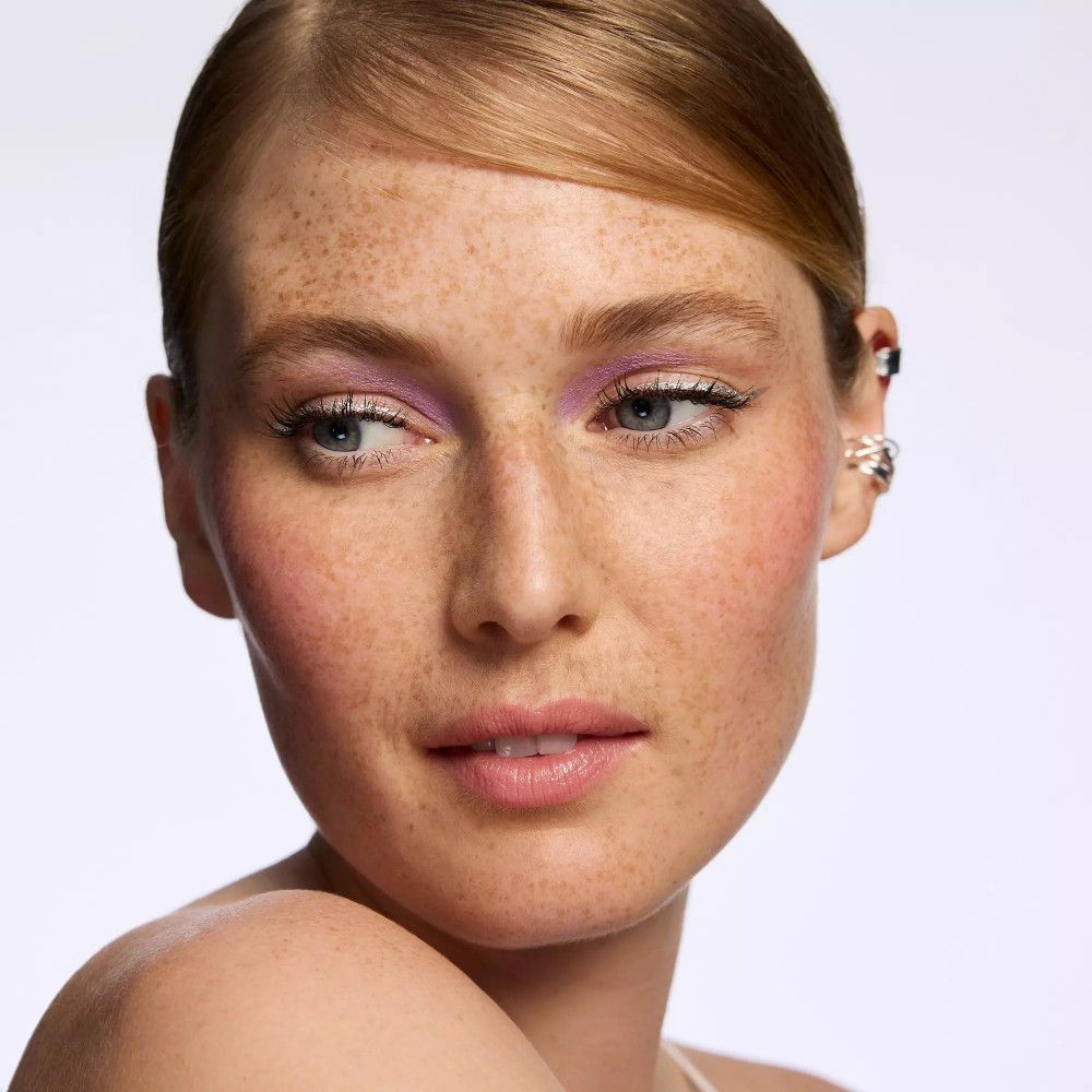 Femme avec des taches de rousseur, fard à paupières. Fard à paupières violet sur les paupières.