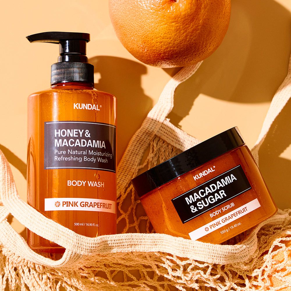 Kundal Body Wash en Body Scrub Macadamia en Pink Grapefruit in oranje flacons.