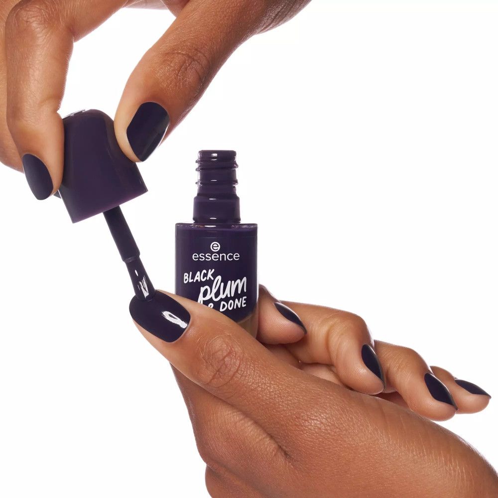 Mains avec ongles vernis prune foncé. Une main tient un flacon de vernis et un pinceau.