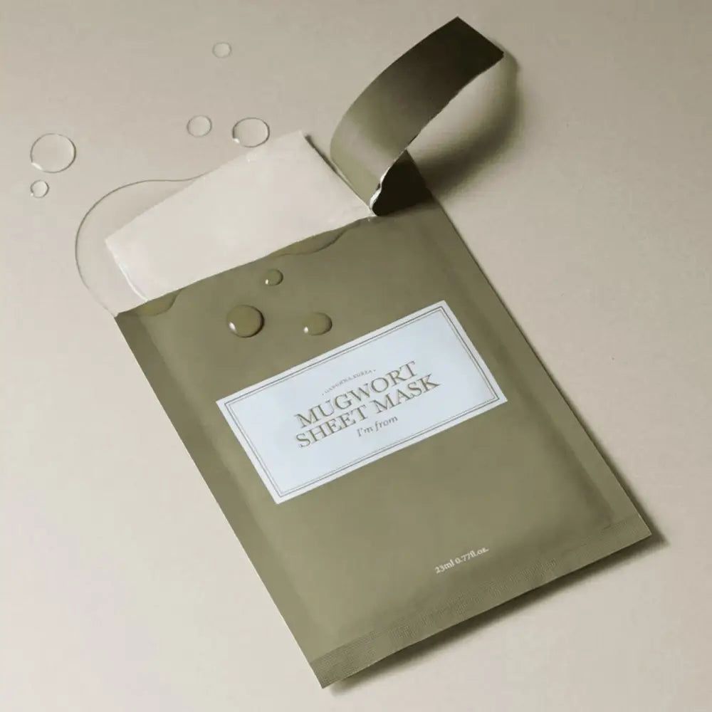 Masque en feuille vert ouvert. Texte : MUGWORT SHEET MASK, I'm from. Gouttes d'eau à côté.