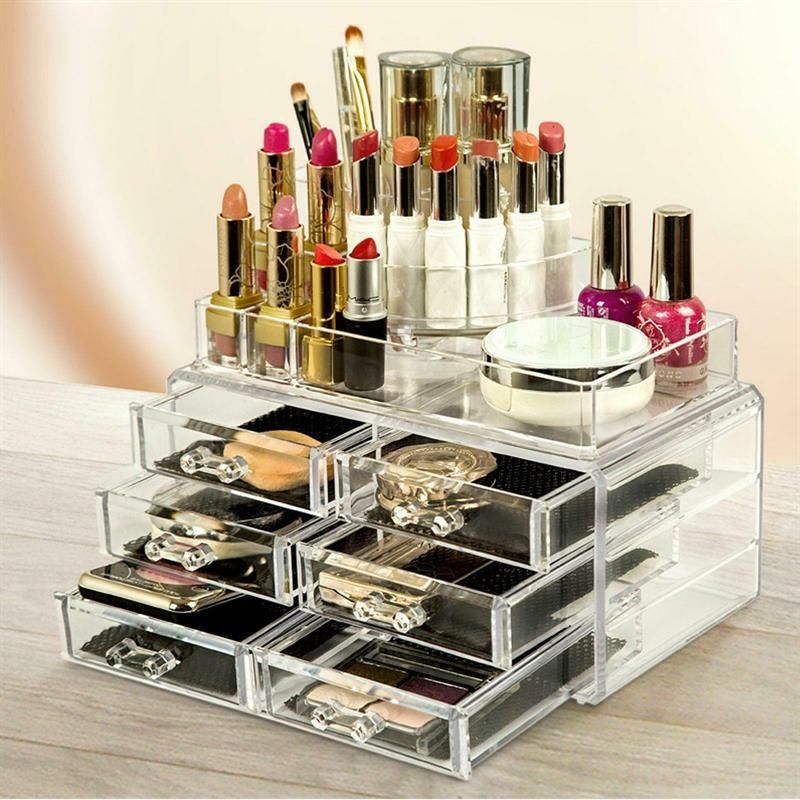 Organisateur de maquillage avec 6 tiroirs et 18 compartiments, rempli de cosmétiques. Structure en acrylique transparent. Fonds noirs.