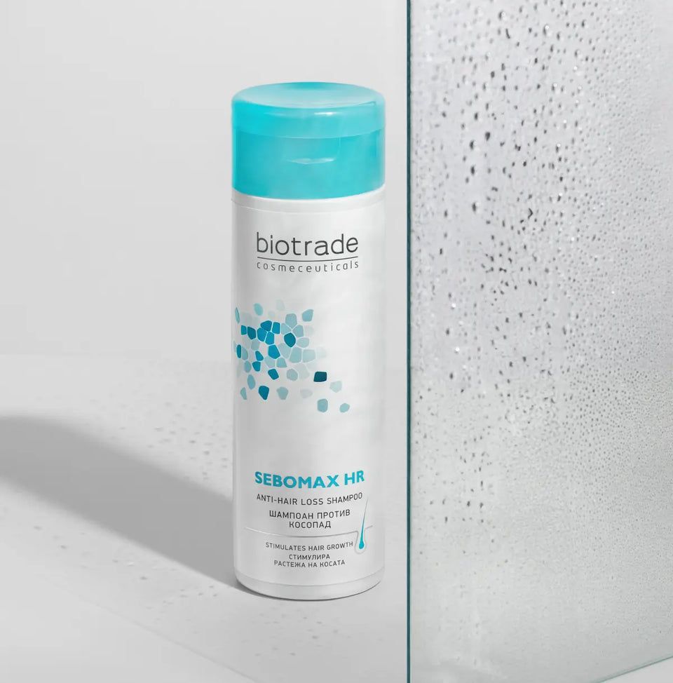 Biotrade Sebomax HR Shampoo, flacon blanc, bouchon bleu. Texte: Sebomax HR, shampooing antichute. Motifs bleus et turquoise.