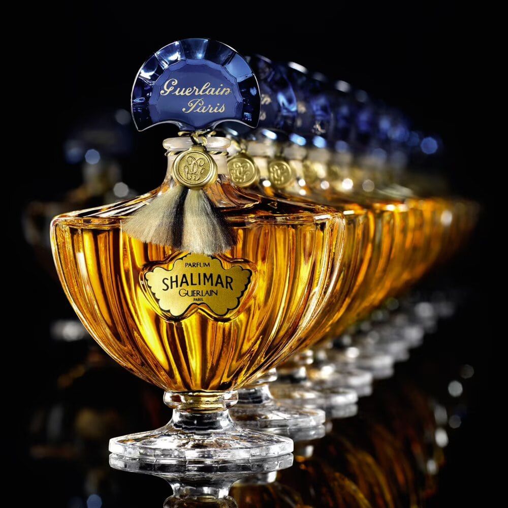 Meerdere Guerlain Shalimar flacons op een rij. Goudkleurig glas, blauwe dop. Opschrift: Shalimar, Guerlain Paris.