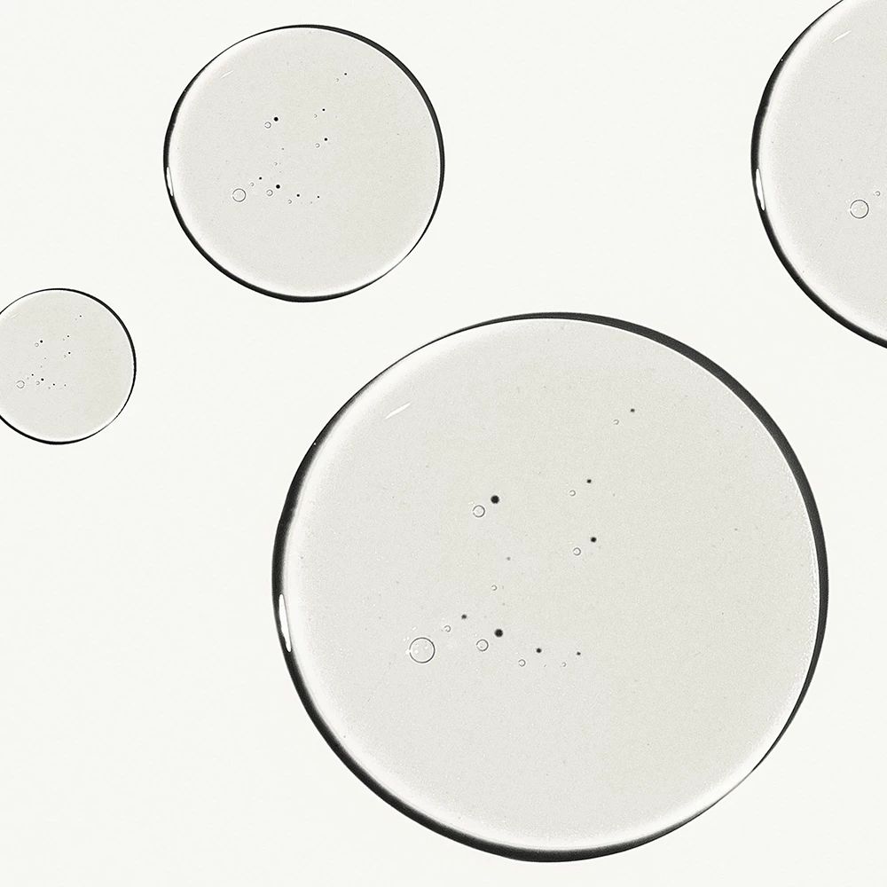 Close-up van vier cirkelvormige, transparante druppels op witte achtergrond.