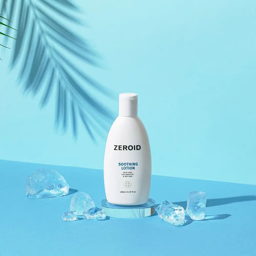 Flacon blanc ZEROID Soothing Lotion sur socle bleu, entouré de glaçons. 200ml/6.76 fl oz. Avec ombre.
