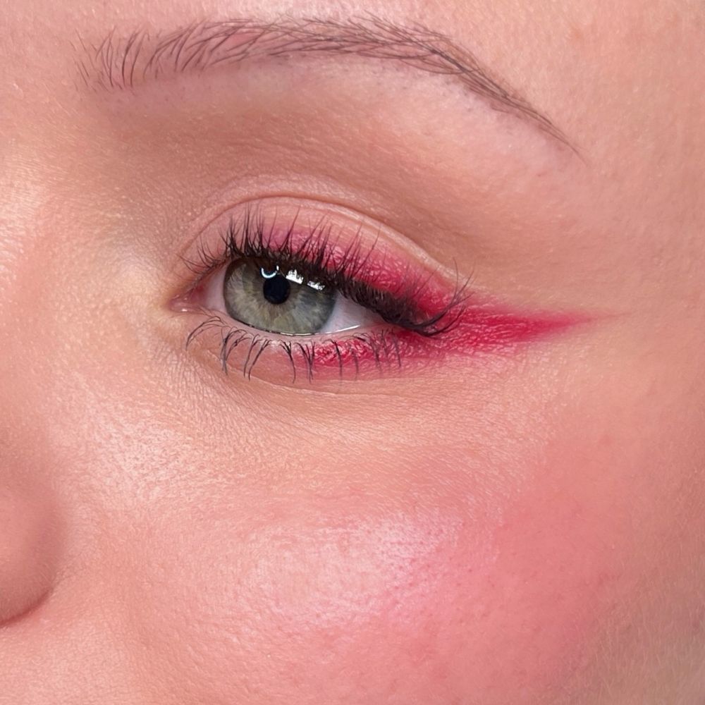 Gros plan sur un œil avec un eye-liner rouge et du mascara. Teint.