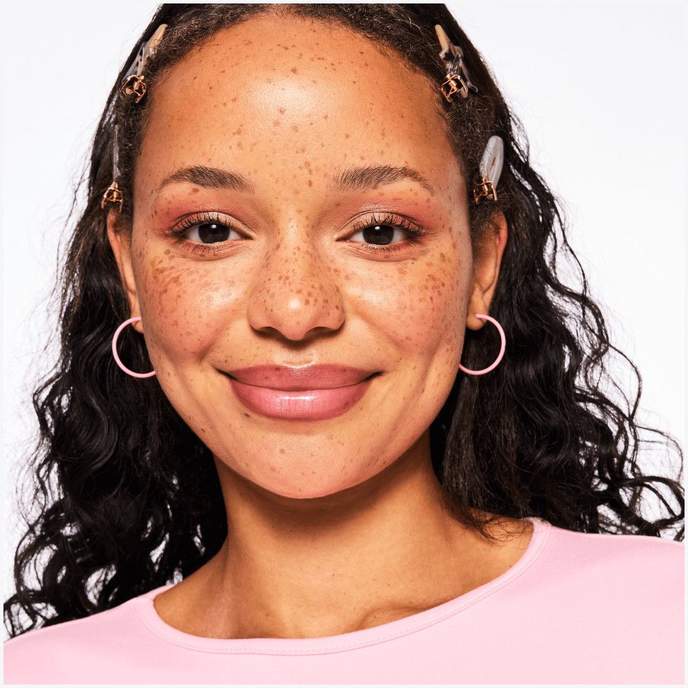 Portret van een vrouw met lippenstift. Ze draagt oorbellen en haarspelden.