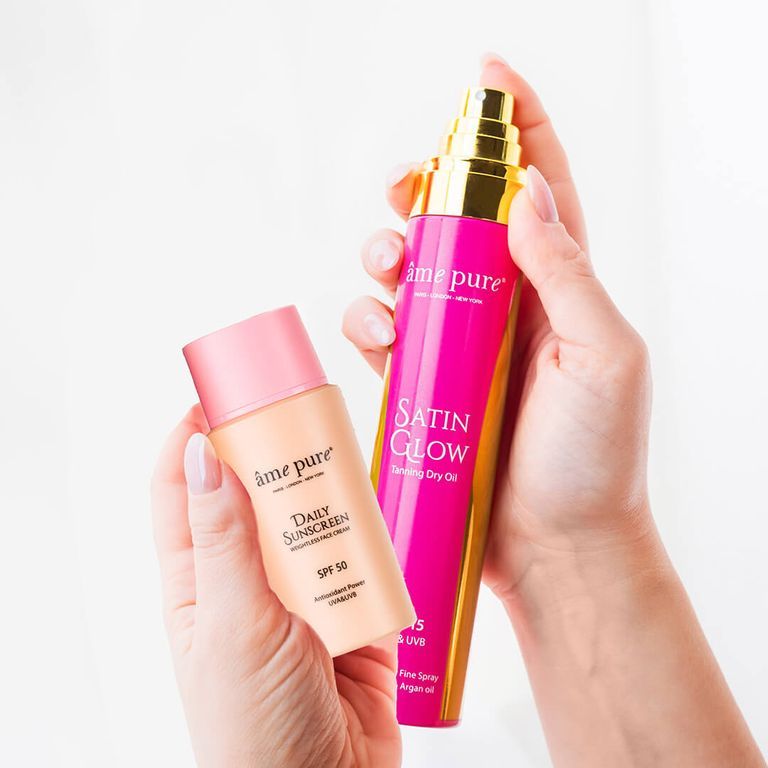 Mains tenant Âme Pure Daily Sunscreen SPF 50 et Satin Glow Tanning Dry Oil.