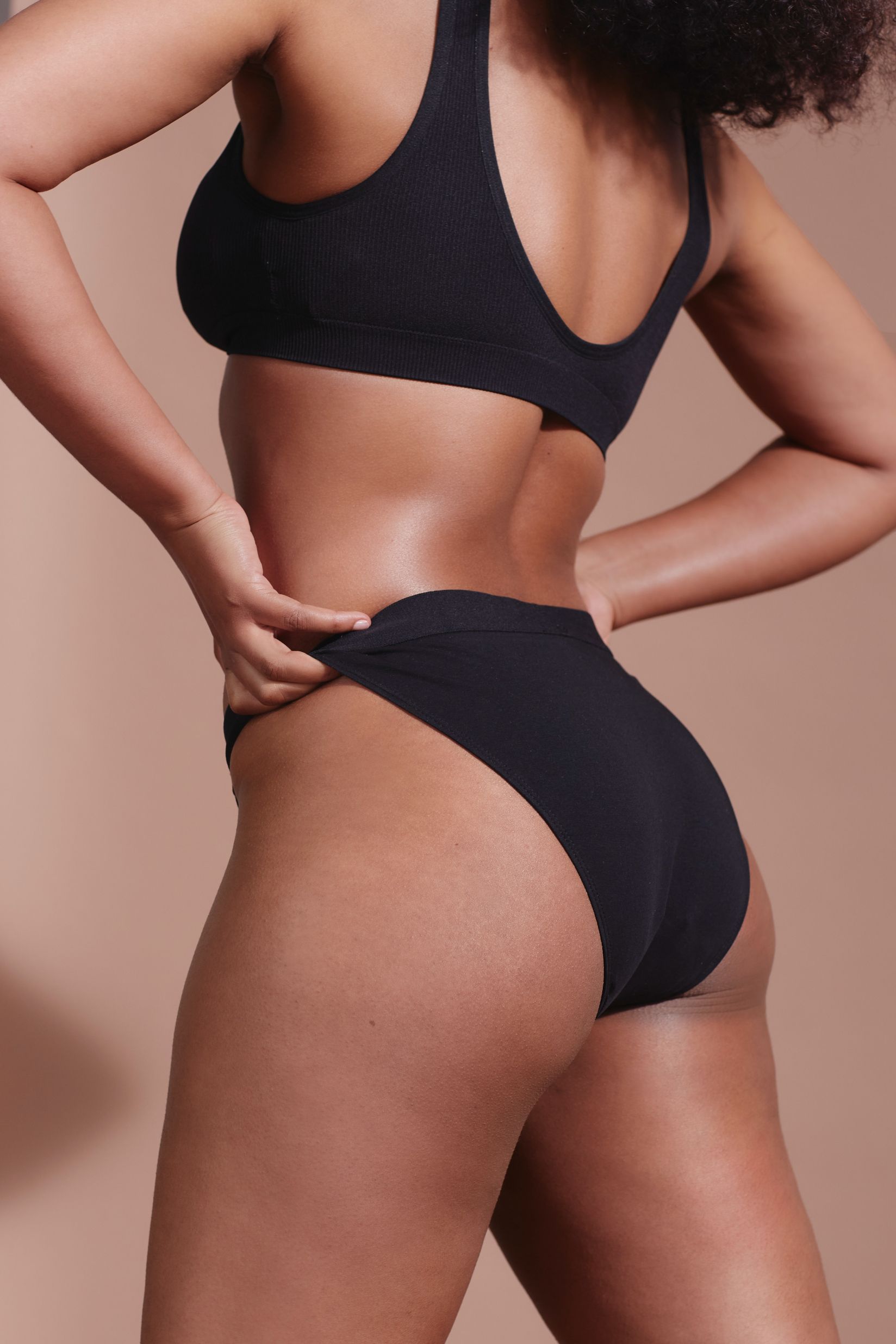 Culotte noire. Femme de dos, mains sur les hanches. Tissu côtelé.