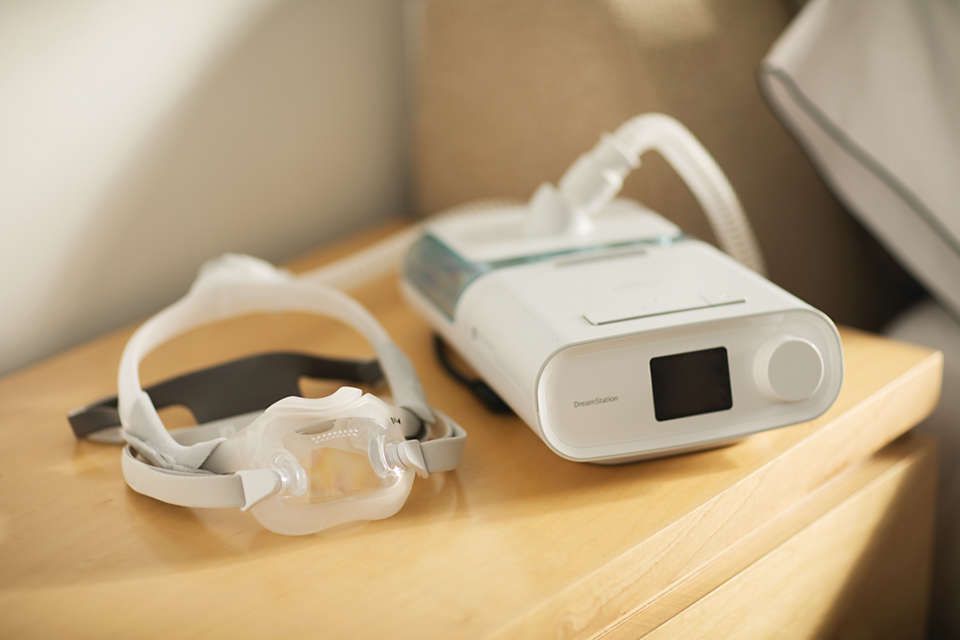Masque Philips CPAP DreamWear et appareil CPAP sur une table de chevet.