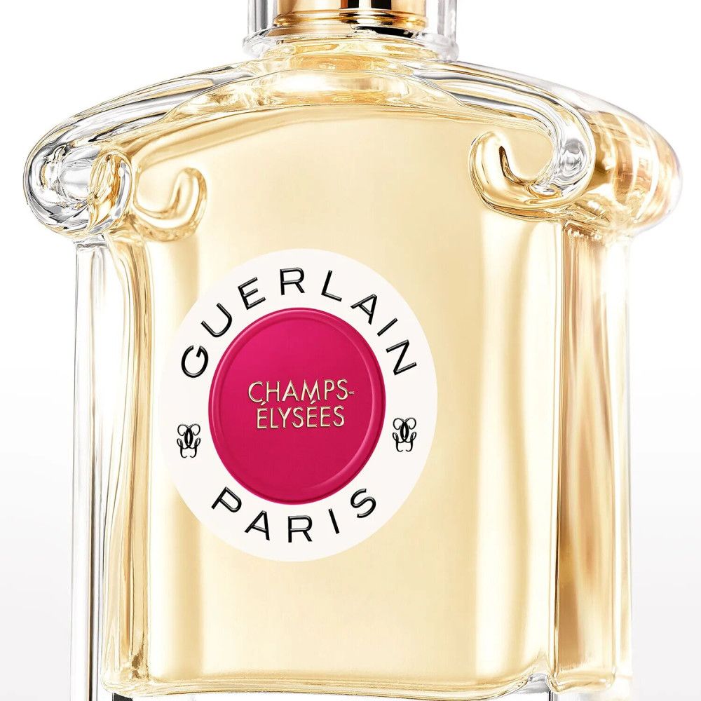 Flacon de parfum avec étiquette ronde. L'étiquette porte "GUERLAIN PARIS" et "CHAMPS-ÉLYSÉES". Le flacon est en verre.