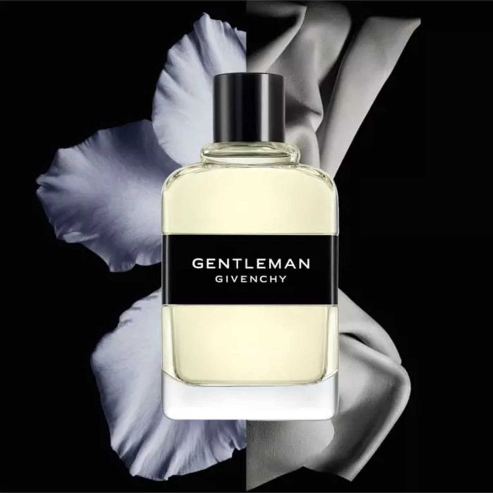 Flacon avec bouchon noir. Étiquette noire avec texte blanc: GENTLEMAN GIVENCHY. Forme rectangulaire. Fond floral.