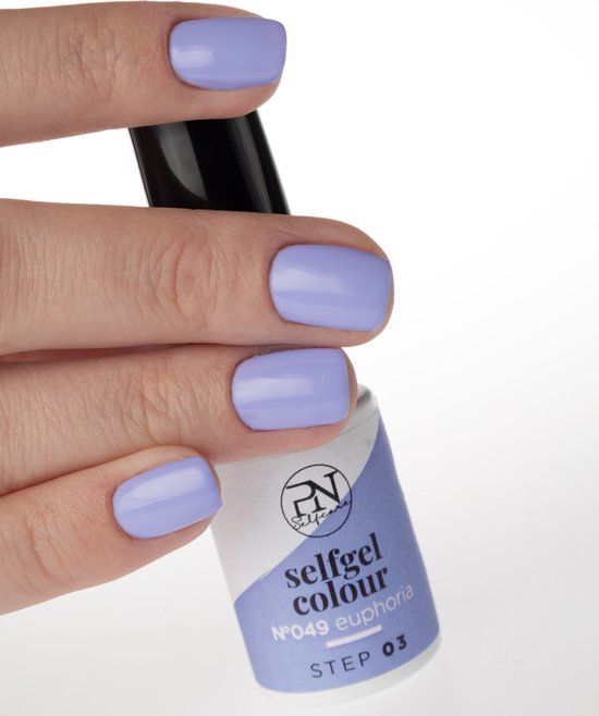 Main avec ongles vernis lilas et flacon PN Selfcare Set Vernis Semi-Permanent Floral Fusion. Étiquette blanche, bouchon noir.