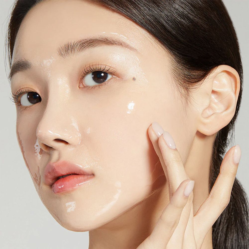 Une femme applique le 'Collagen Night Wrapping Mask' sur son visage.