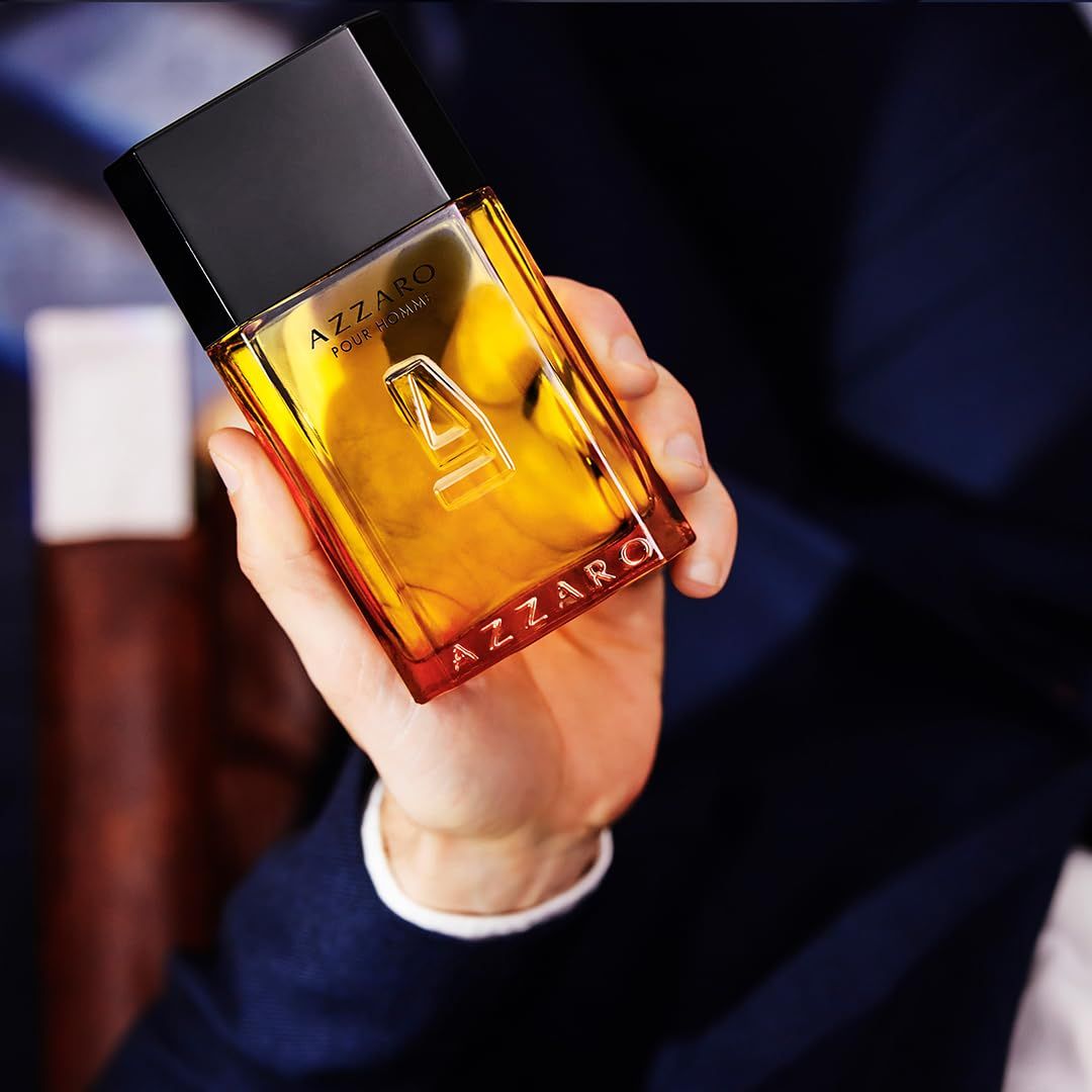 Flacon Azzaro Pour Homme Eau de Toilette en verre avec bouchon noir, tenu dans une main.