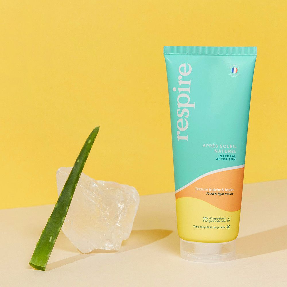 Tube turquoise et jaune avec inscription blanche "Respire". Feuille d'aloe vera et bloc de glace à côté. Drapeau français.