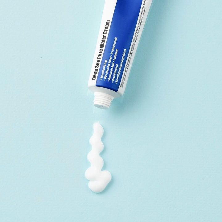 Crème sortant d'un tube. Produit blanc. Fond bleu clair. Texte: Deep Sea Pure Water Cream.