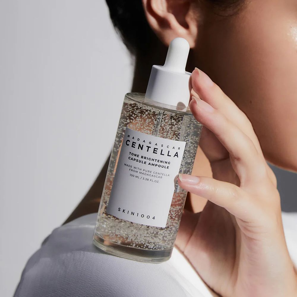 Flacon en verre transparent avec bouchon blanc et pipette. Étiquette avec texte. Tenue en main.