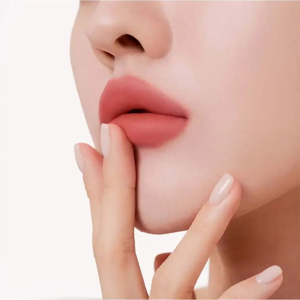 Close-up van lippen met lippenstift. Vinger raakt de lippen aan. Lichte huidskleur.