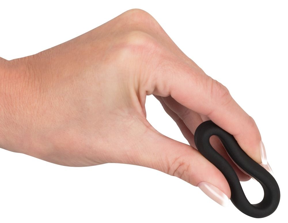 Un anneau flexible noir en silicone tenu par une main.