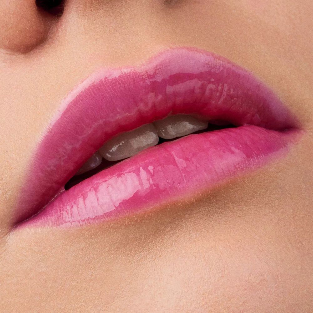 Close-up van lippen met glanzende, roze lipolie. Open lippen, tanden zichtbaar.