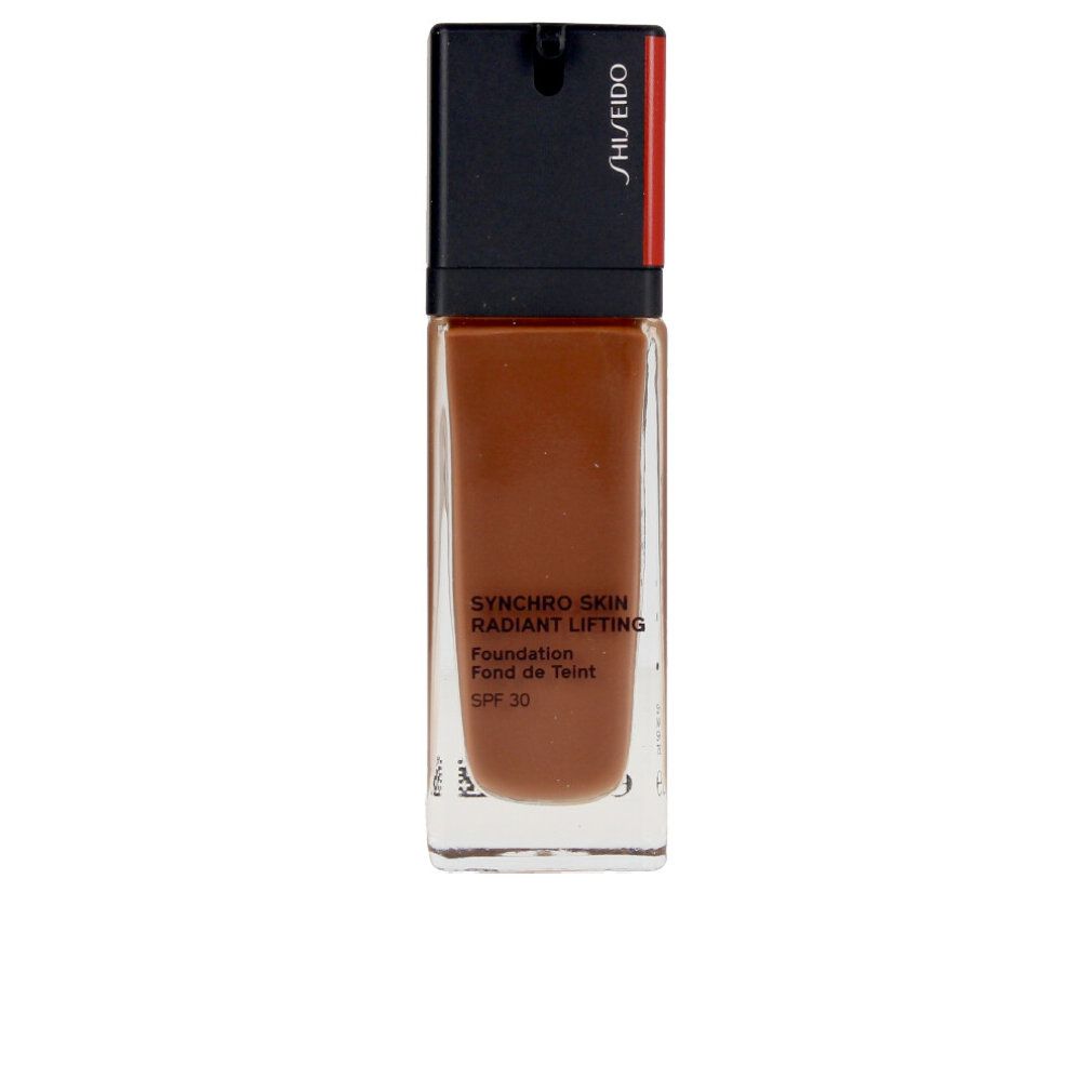 Flacon de fond de teint brun. Bouchon noir avec accent rouge. Inscription: Synchro Skin Radiant Lifting Foundation, SPF 30.