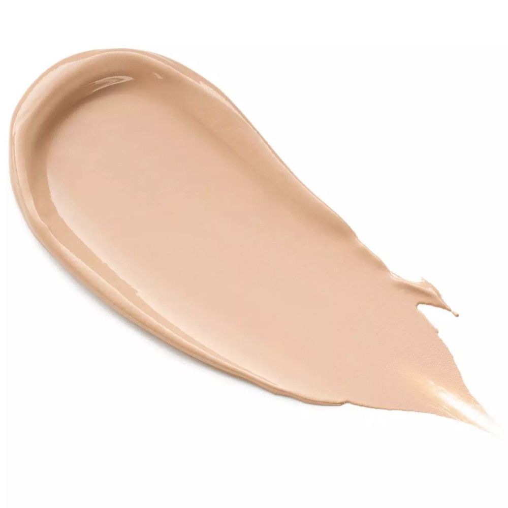 Crème beige étalée. Texture brillante. Forme d'une goutte. Fond blanc.