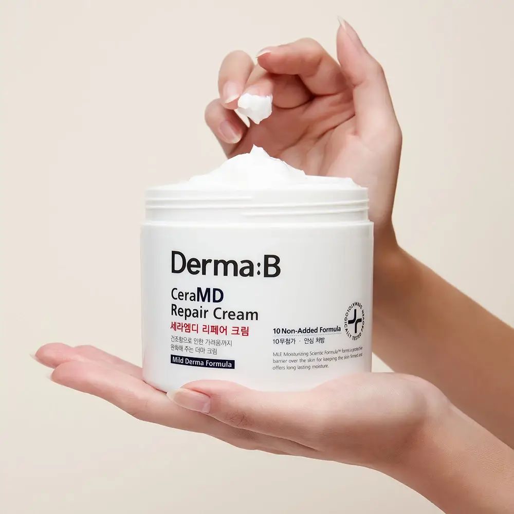 Open pot met crème, vastgehouden door handen. Opschrift: Derma:B CeraMD Repair Cream.