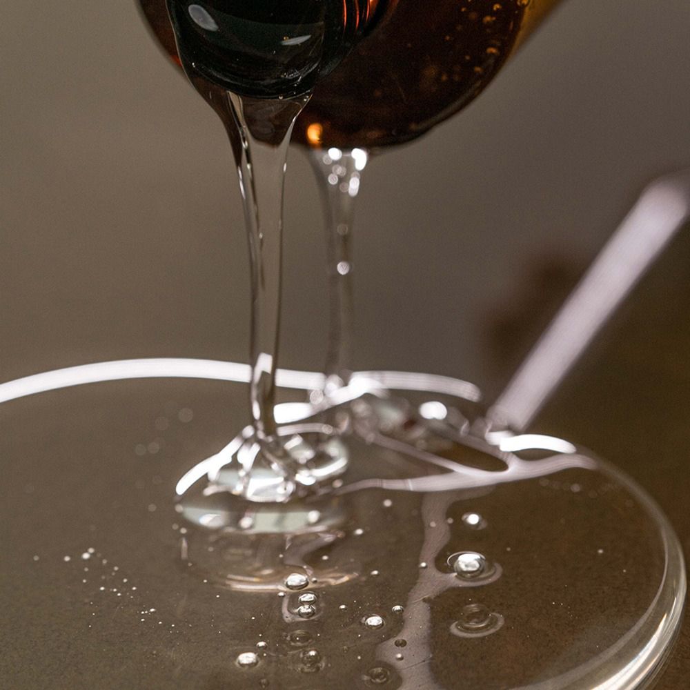 Heldere shampoo wordt uit een fles gegoten. Vloeistof druppelt op een oppervlak.