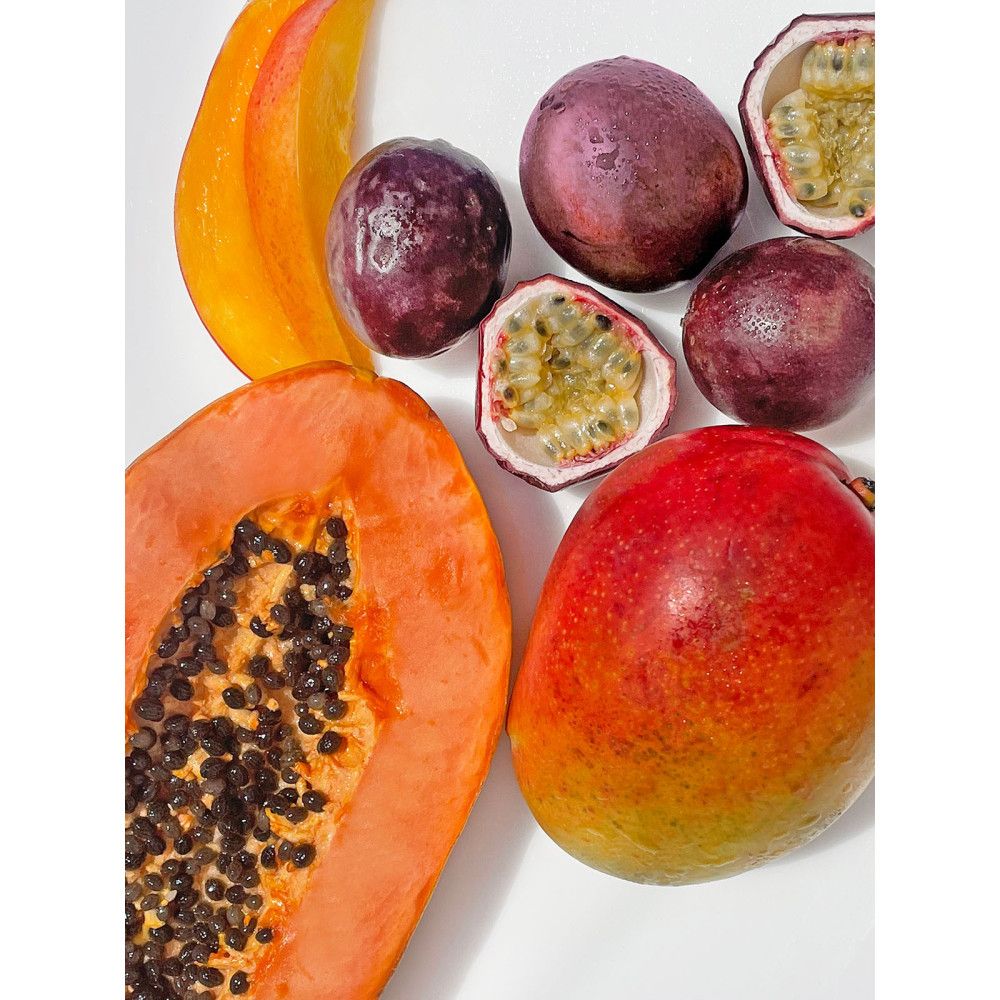 Papaye, mangue et fruits de la passion sur fond blanc. Vue de dessus. Certains fruits sont coupés en deux.