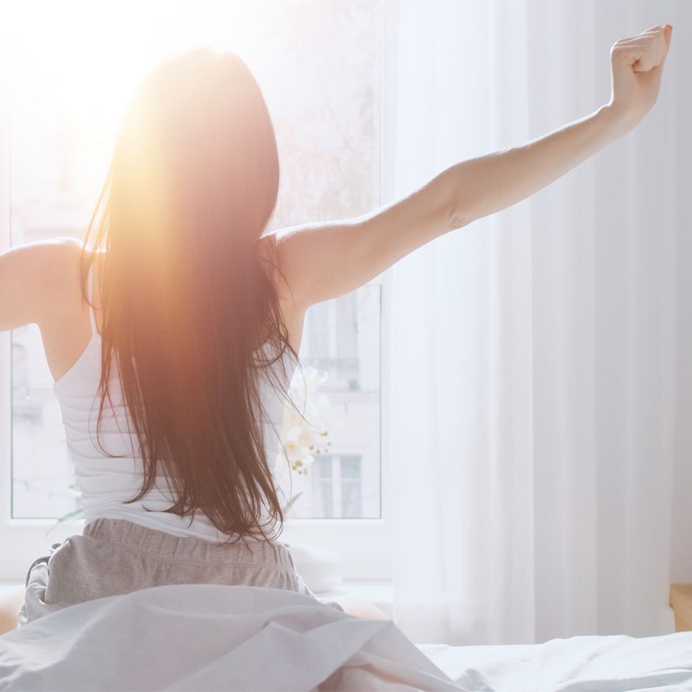 Persoon die zich uitrekt in bed. Lichte omgeving.