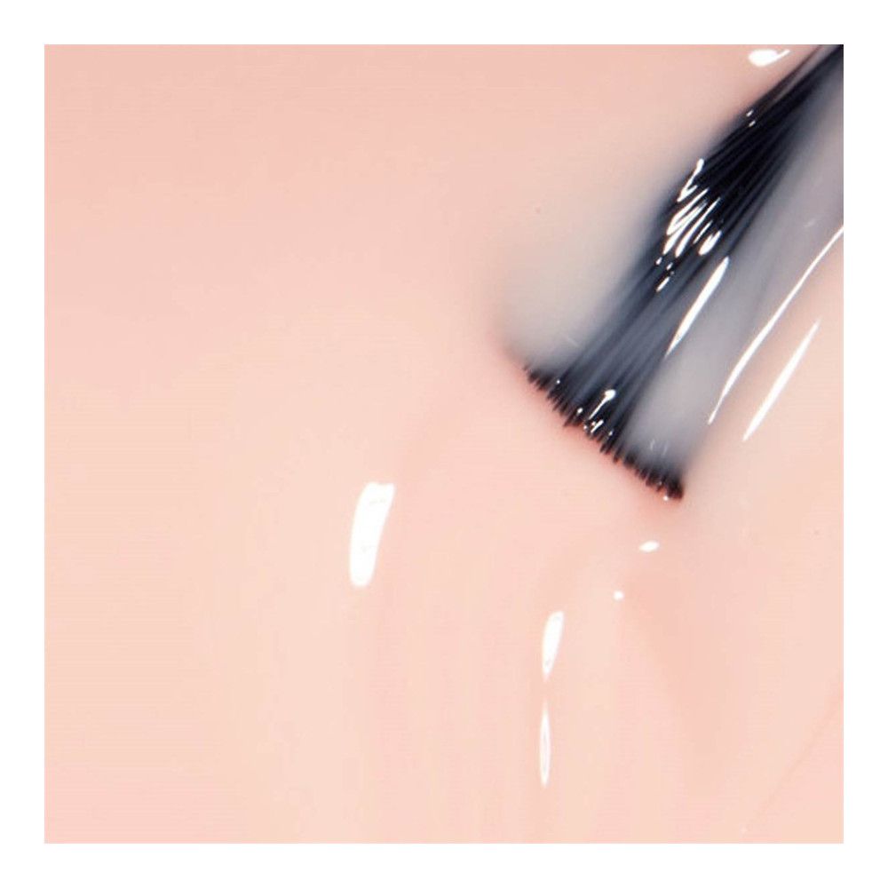 Applicateur de vernis à ongles avec vernis rose clair. Soies foncées. Coulures de vernis.