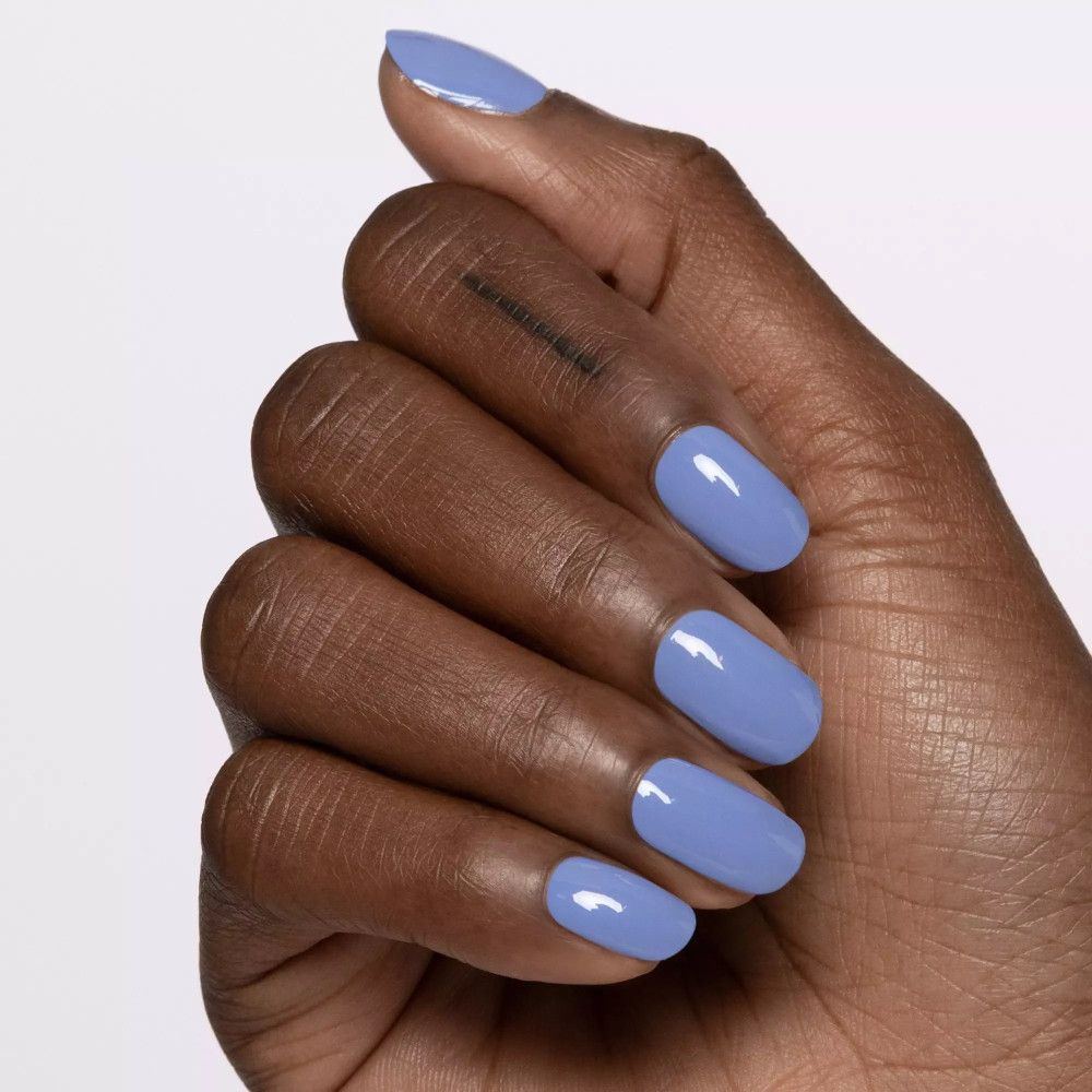 Main avec ongles vernis en bleu clair. Forme ovale, brillant. Sur fond clair.