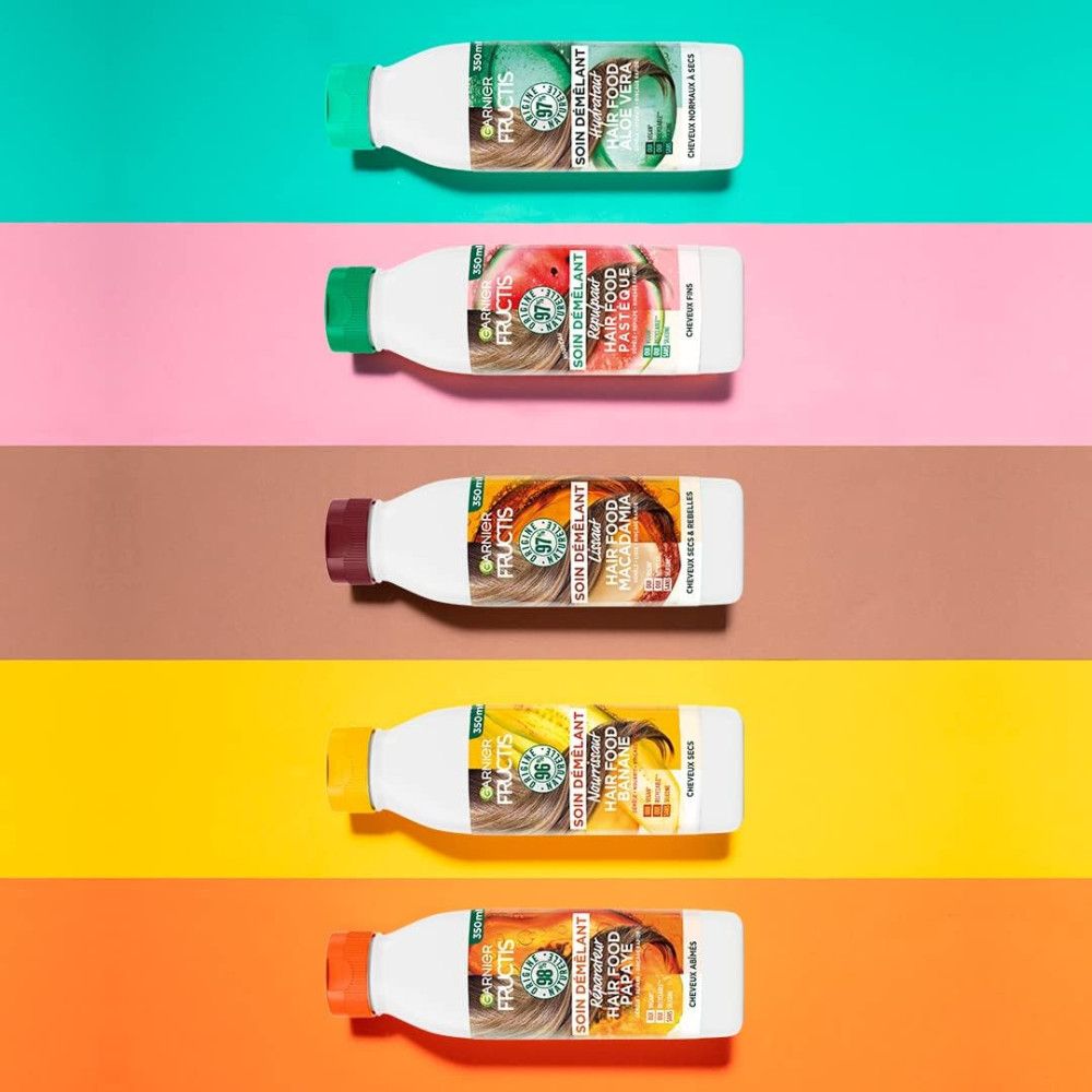 Cinq bouteilles de revitalisant avec des bouchons colorés. Inscription: Garnier Fructis Hair Food. Différentes variétés de fruits.