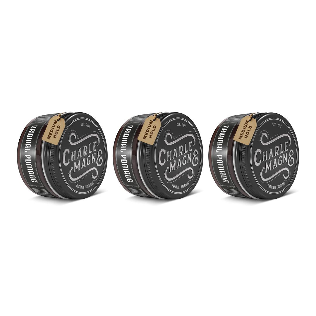 Trois boîtes rondes noires avec couvercles. Chaque boîte porte l'inscription "CHARLE MAGNE" et "ORIGINAL POMADE". Chaque boîte a une étiquette "MEDIUM HOLD".