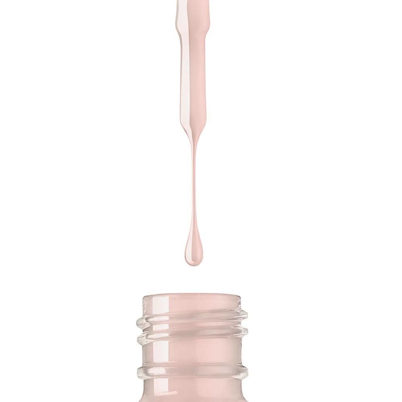 Close-up van een nagellakfles. Kwastje met druppel lichtroze nagellak. Open fles.