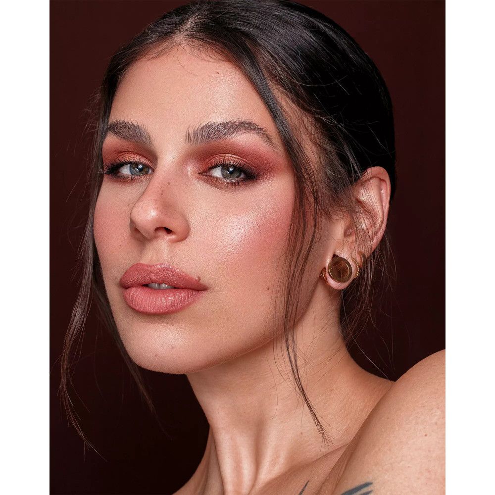 Gros plan d'une femme avec du maquillage. Fard à paupières marron, lèvres et blush roses.