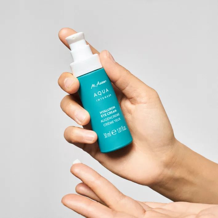 Hand houdt turquoise fles vast. Opschrift: M. Asam AQUA INTENSE Hyaluron Eye Cream.