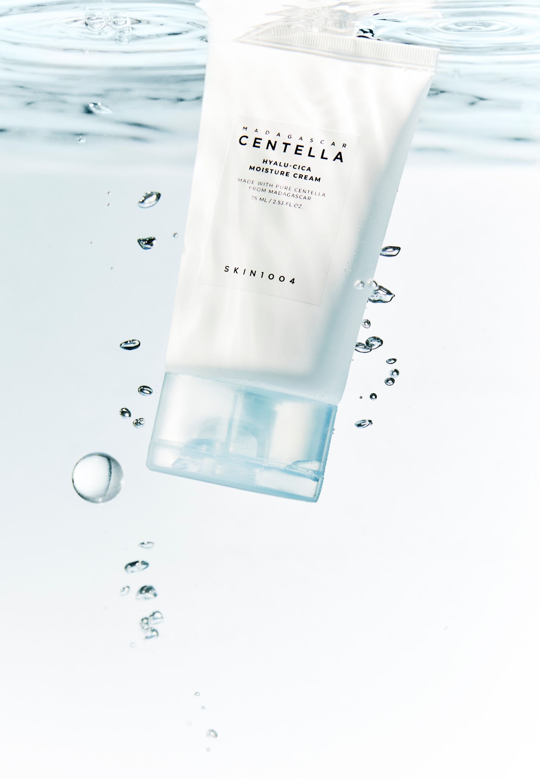 Witte tube in water. Tekst: MADAGASCAR CENTELLA, HYALU-CICA MOISTURE CREAM, SKIN1004. Waterbellen.