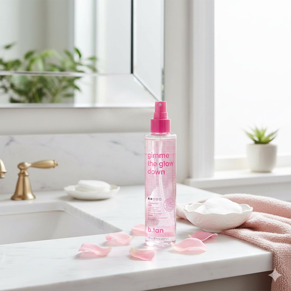 Flacon de brume autobronzante avec vaporisateur rose. Des pétales de rose sur une surface en marbre. Lavabo et miroir en arrière-plan.