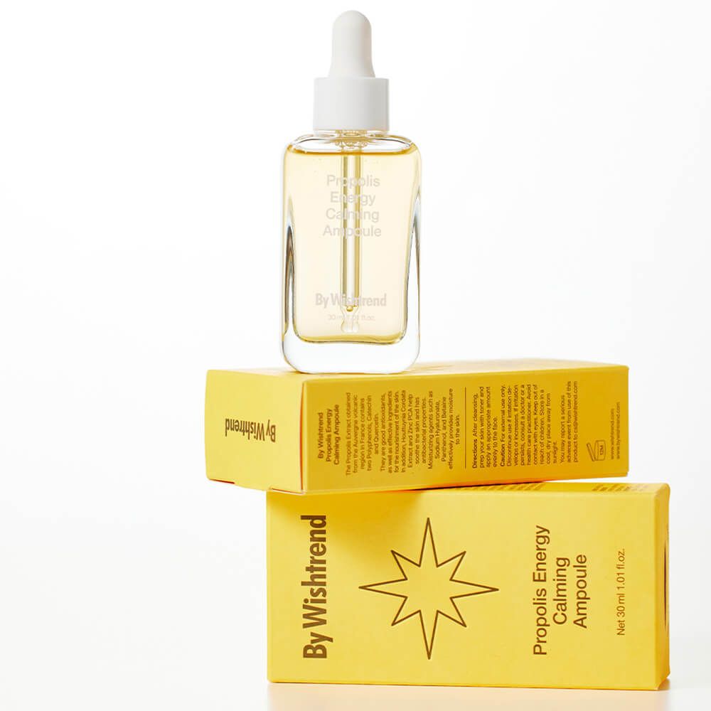 Flacon en verre avec liquide jaunâtre sur deux boîtes jaunes. Inscription : By Wishtrend, Propolis Energy Calming Ampoule.