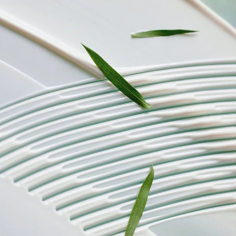 Fond de crème blanc avec des feuilles vertes. Crème appliquée en forme de vagues. Feuilles sur la crème.