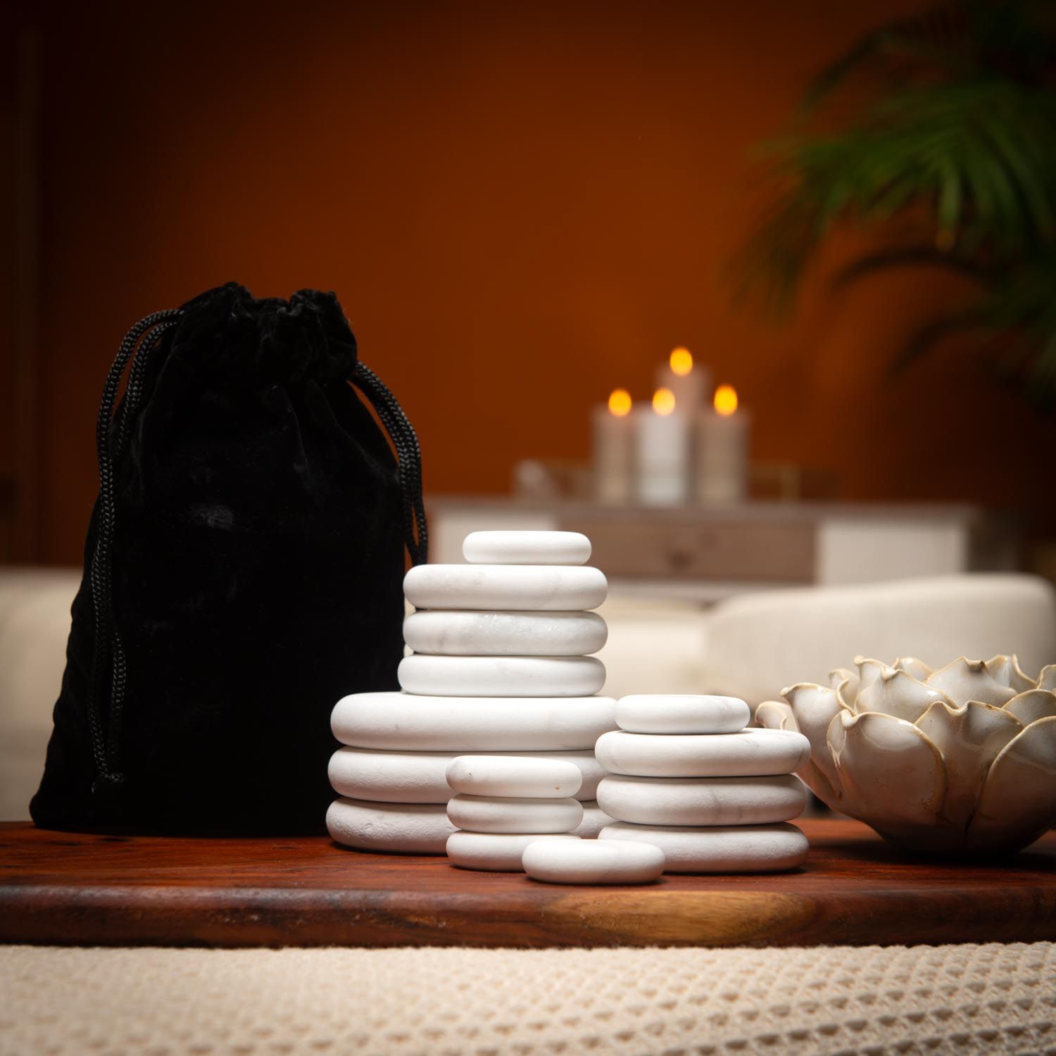 Pierres blanches ovales et un sac noir sur une table. Bougies en arrière-plan.