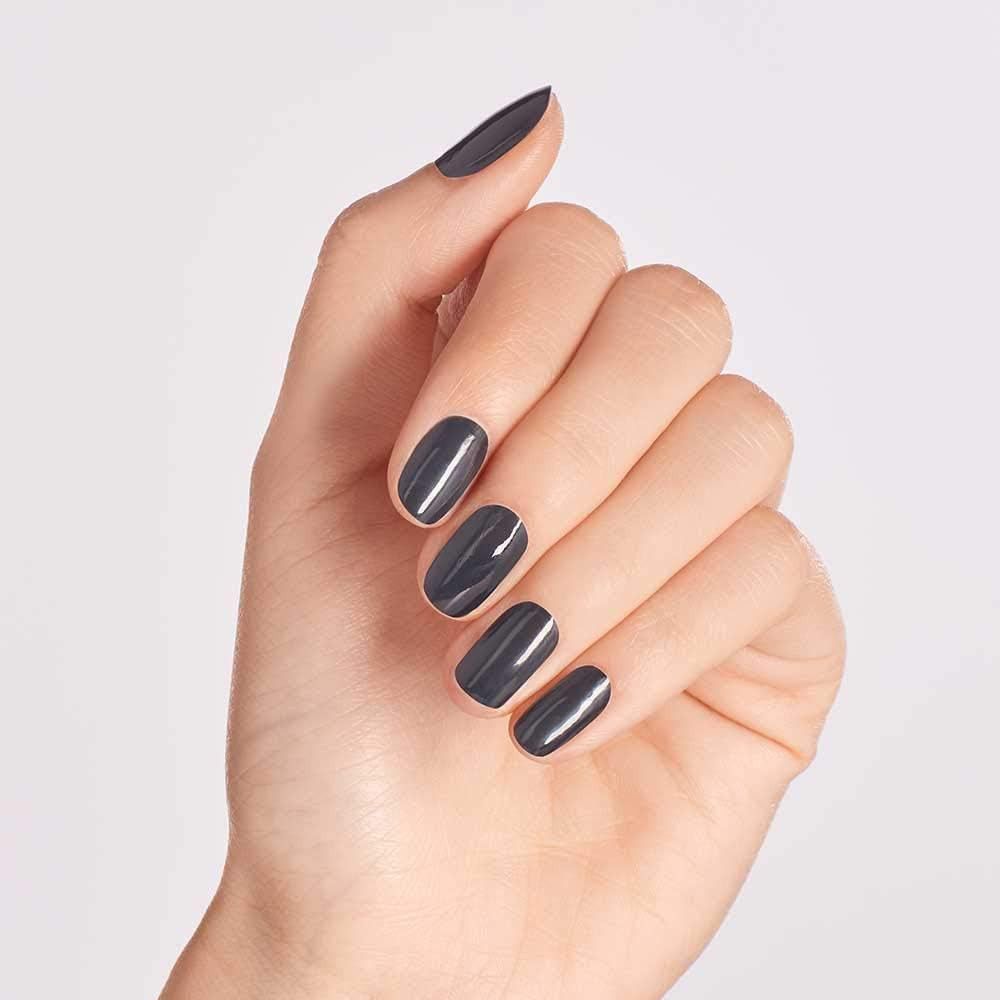 Main avec ongles vernis en gris. Finition brillante. Sur fond clair.