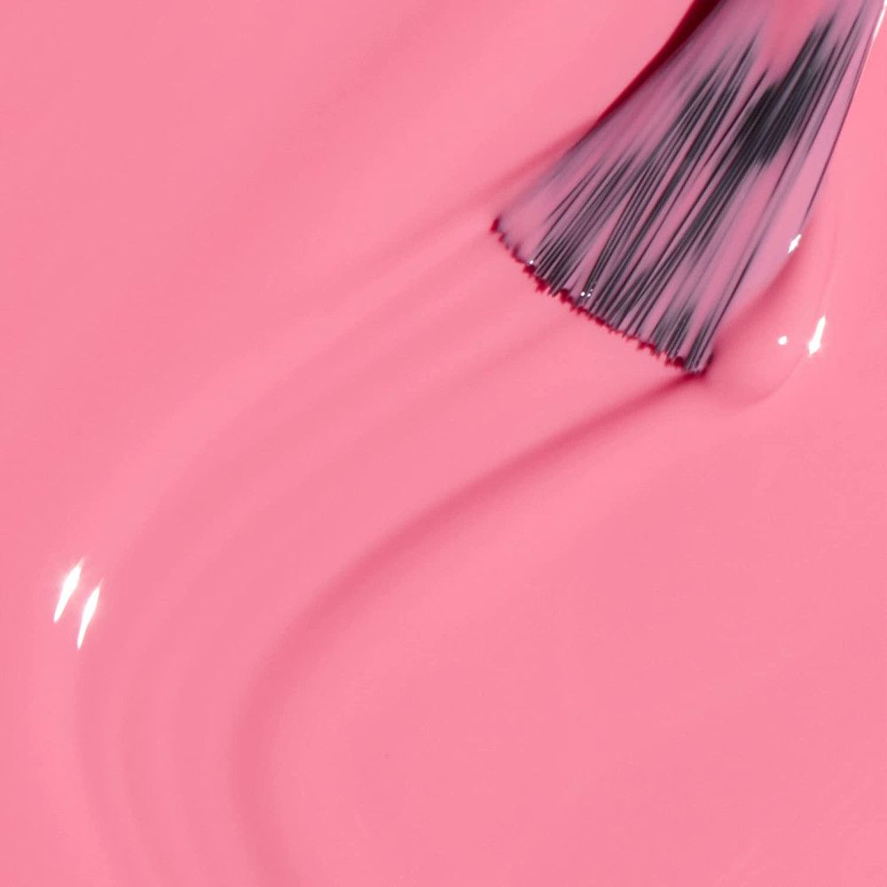 Pinceau avec vernis à ongles rose. Le coup de pinceau crée une surface lisse et ondulée. Le vernis est brillant.