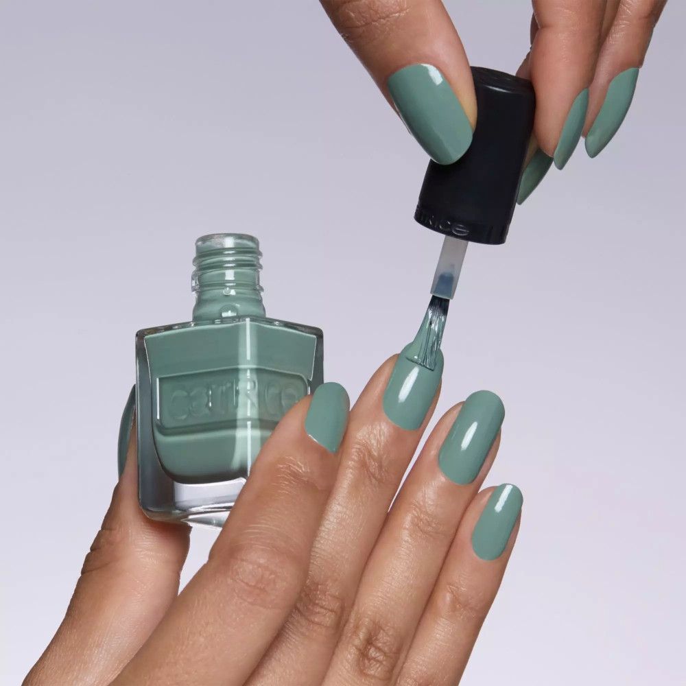 Main vernissant les ongles avec du vernis. Couleur vert clair. Marque Catrice.