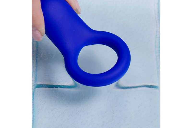 Blauwe siliconen ring, vastgehouden door een hand. De ring heeft een ovale vorm met een opening.