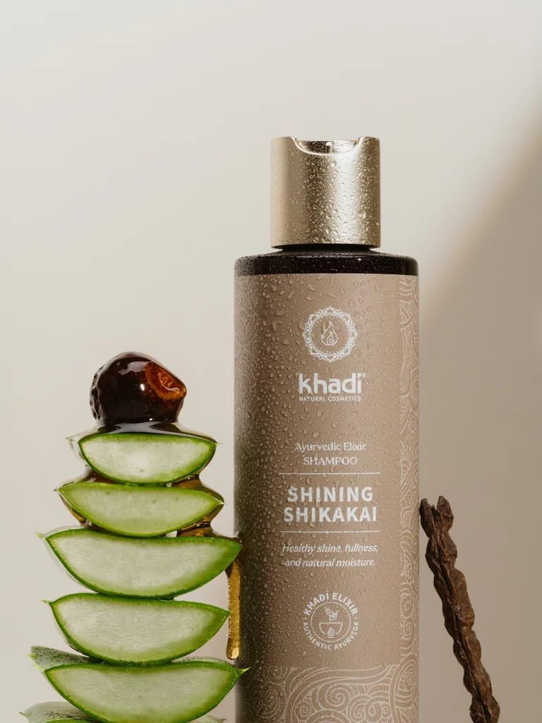 Khadi Shining Shikakai Shampoo fles met dop. Naast aloë vera en een stuk hout. Tekst: Ayurvedisch Elixer, natuurlijke hydratatie.