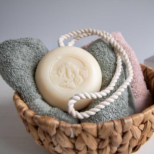 Savon rond avec cordon dans un panier avec des serviettes. Savon avec gravure.